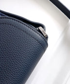 Navy Dior bag close-up of pebbled leather side and curved flap edge.