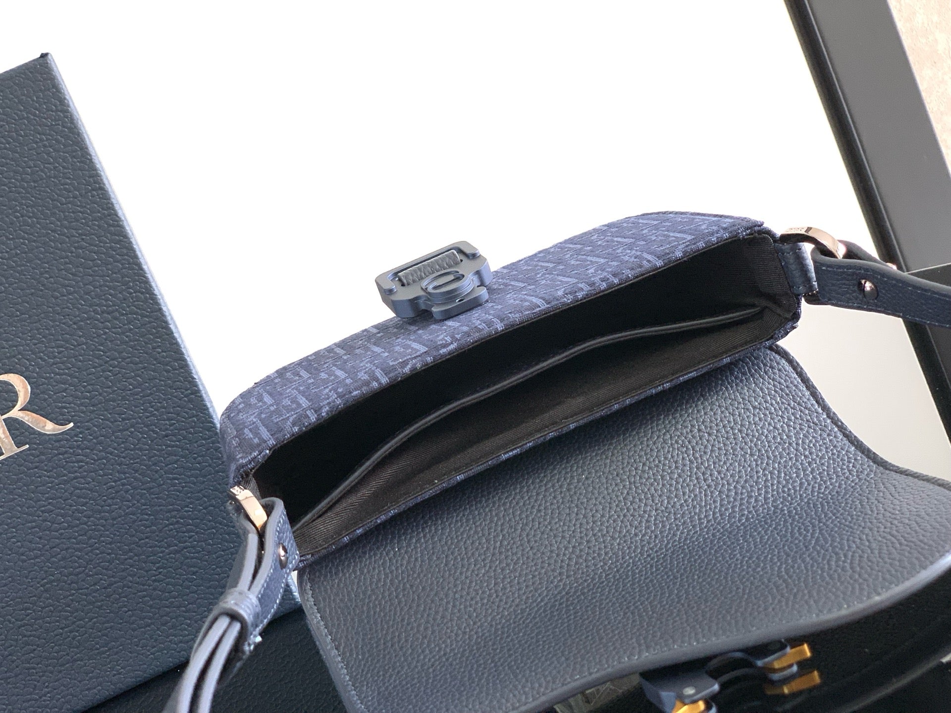 Navy Dior bag open-top view with interior lining and front flap hardware.