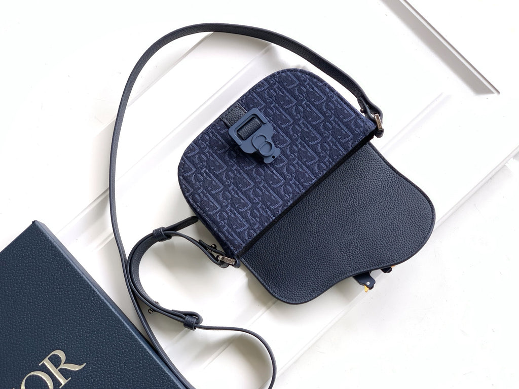 Navy Dior crossbody bag with flap top, patterned panel, and long adjustable strap.