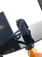 Navy Dior shoulder bag with flap and patterned fabric exterior, adjustable strap.