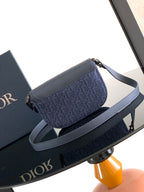 Navy Dior crossbody bag with flap front and long shoulder strap, gold-tone details.
