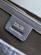 Navy Dior bag close-up of embossed “DIOR” logo on pebbled leather panel.