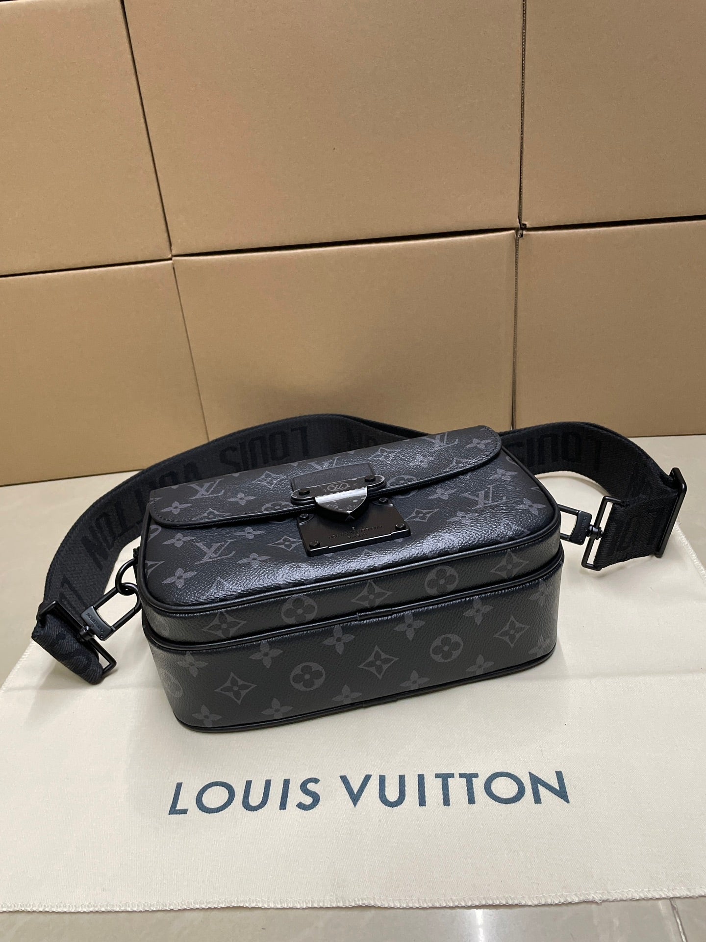 Dark monogram crossbody bag with top flap and metal buckle, adjustable strap