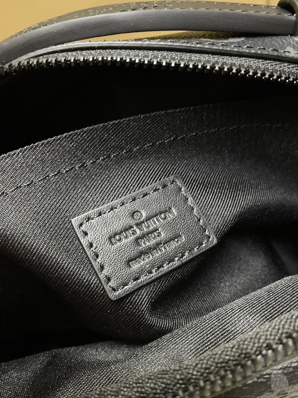Louis Vuitton monogram bag inner label stitched on dark fabric near zipper