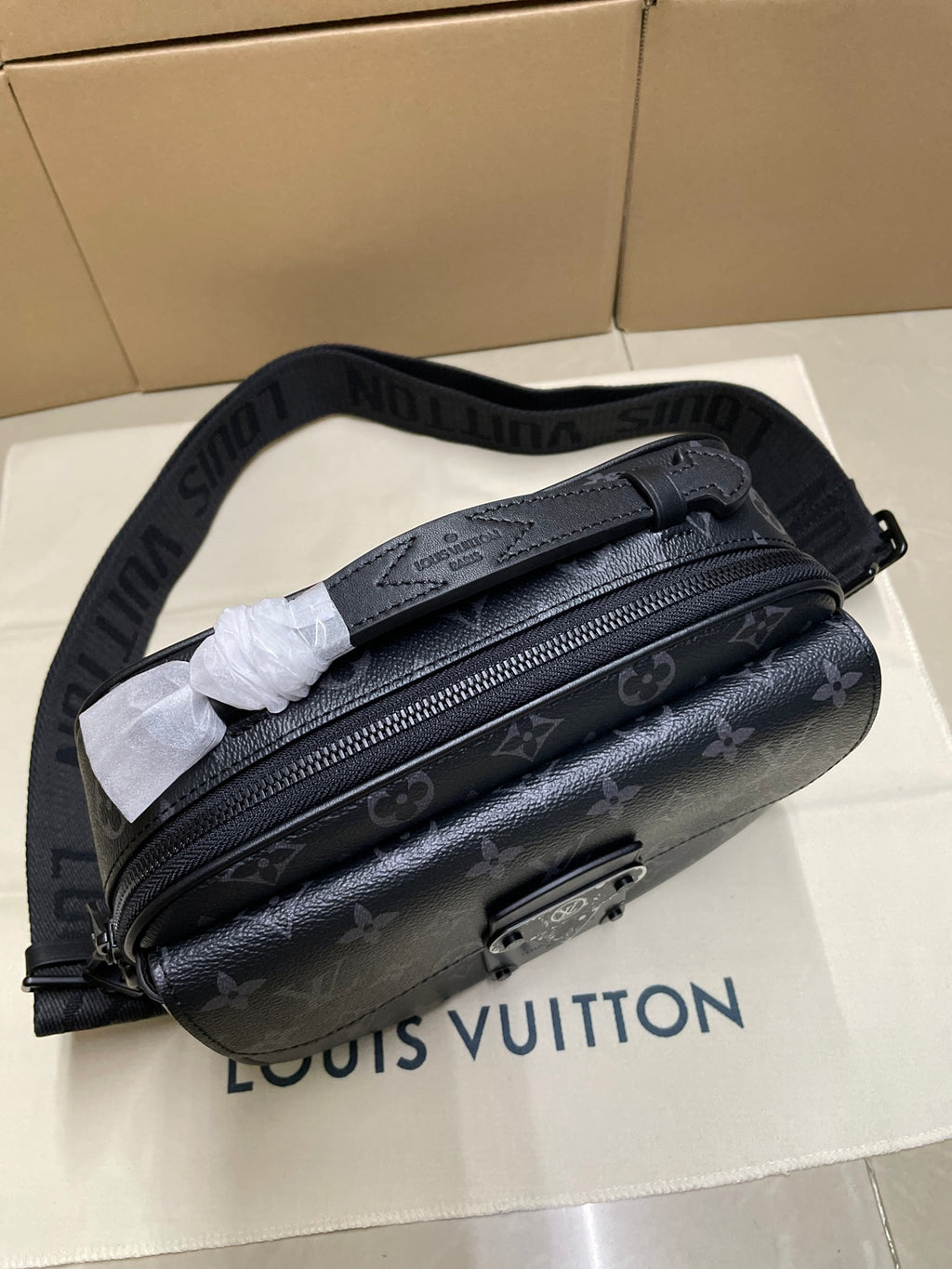 Dark monogram crossbody bag with front zipper and adjustable web strap