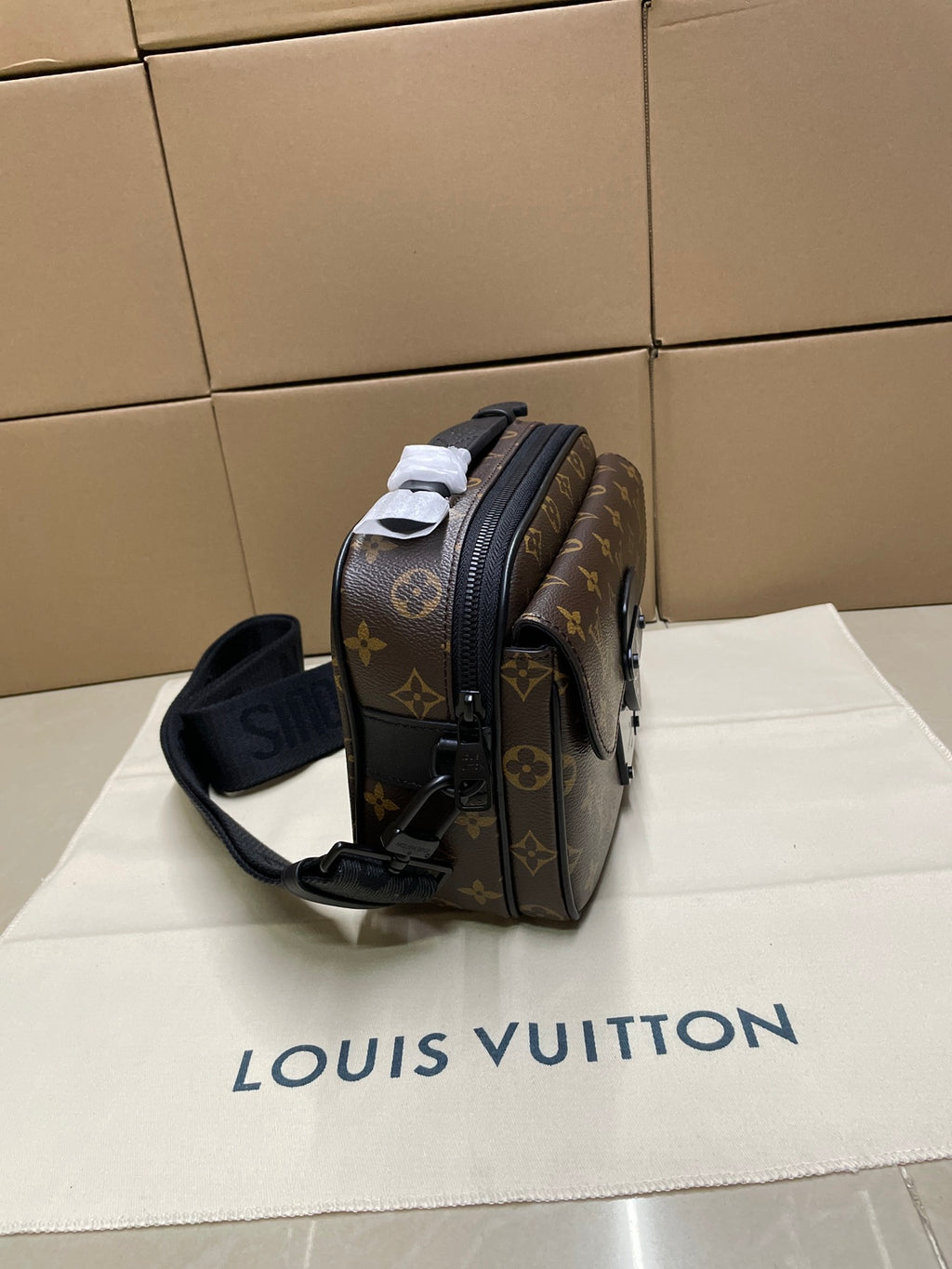 Louis Vuitton monogram crossbody bag from side angle with black strap and trim