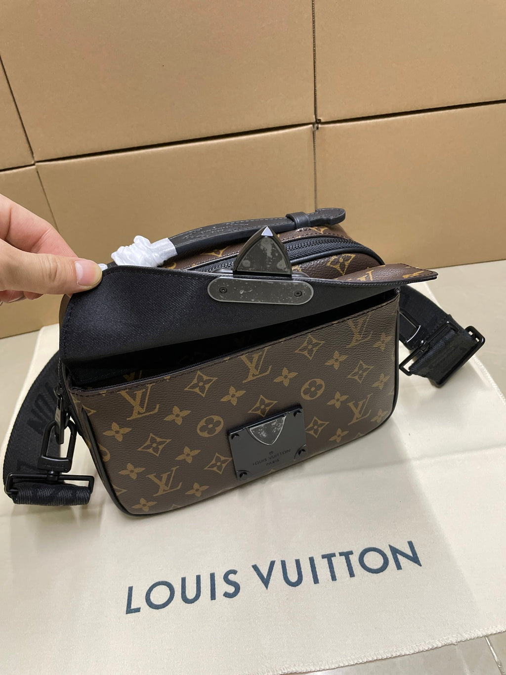 Louis Vuitton monogram crossbody bag held up, showing front flap and hardware