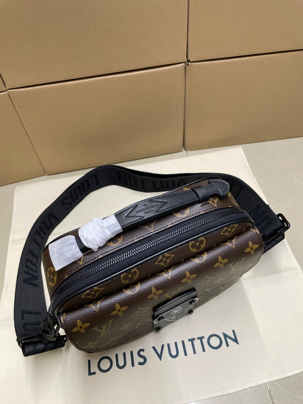 Louis Vuitton monogram crossbody bag with top zip and black strap, viewed from above