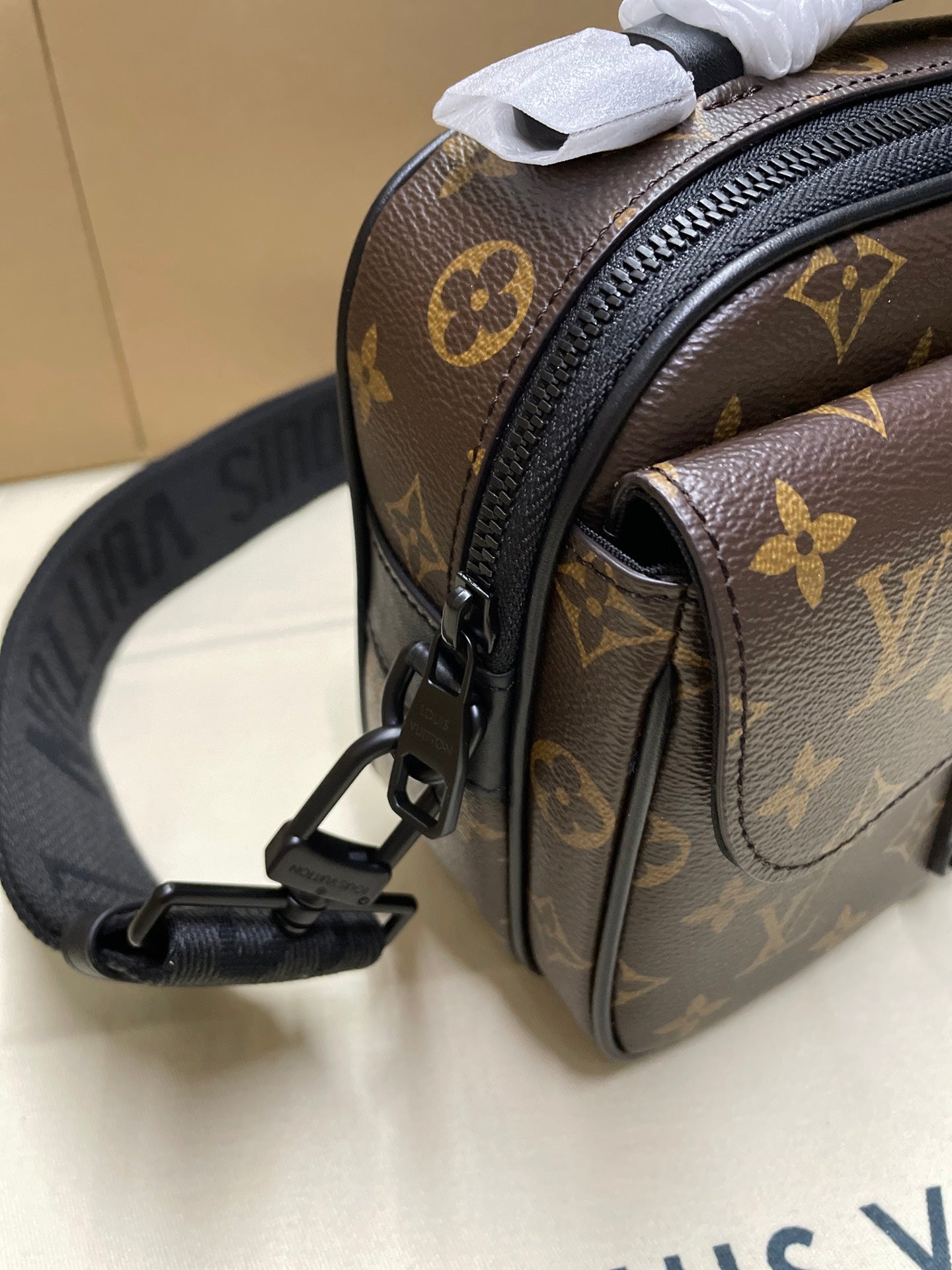 Louis Vuitton monogram crossbody bag close-up of side pocket, zipper, and leather trim