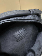 Louis Vuitton men's bag close-up of stitched logo patch and zipper trim on dark fabric