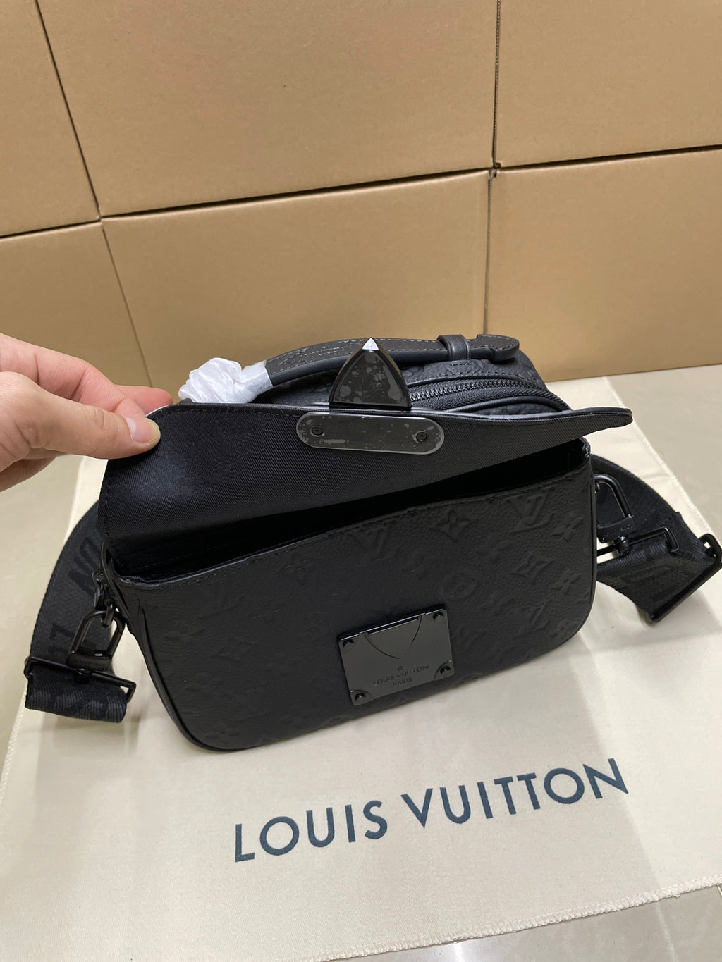 Louis Vuitton men's crossbody bag held open, dark monogram front with zip and logo plate