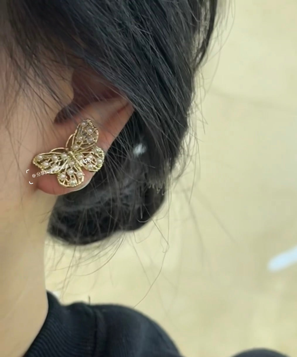 Gold butterfly stud earrings with white pearl and crystal accents on ear