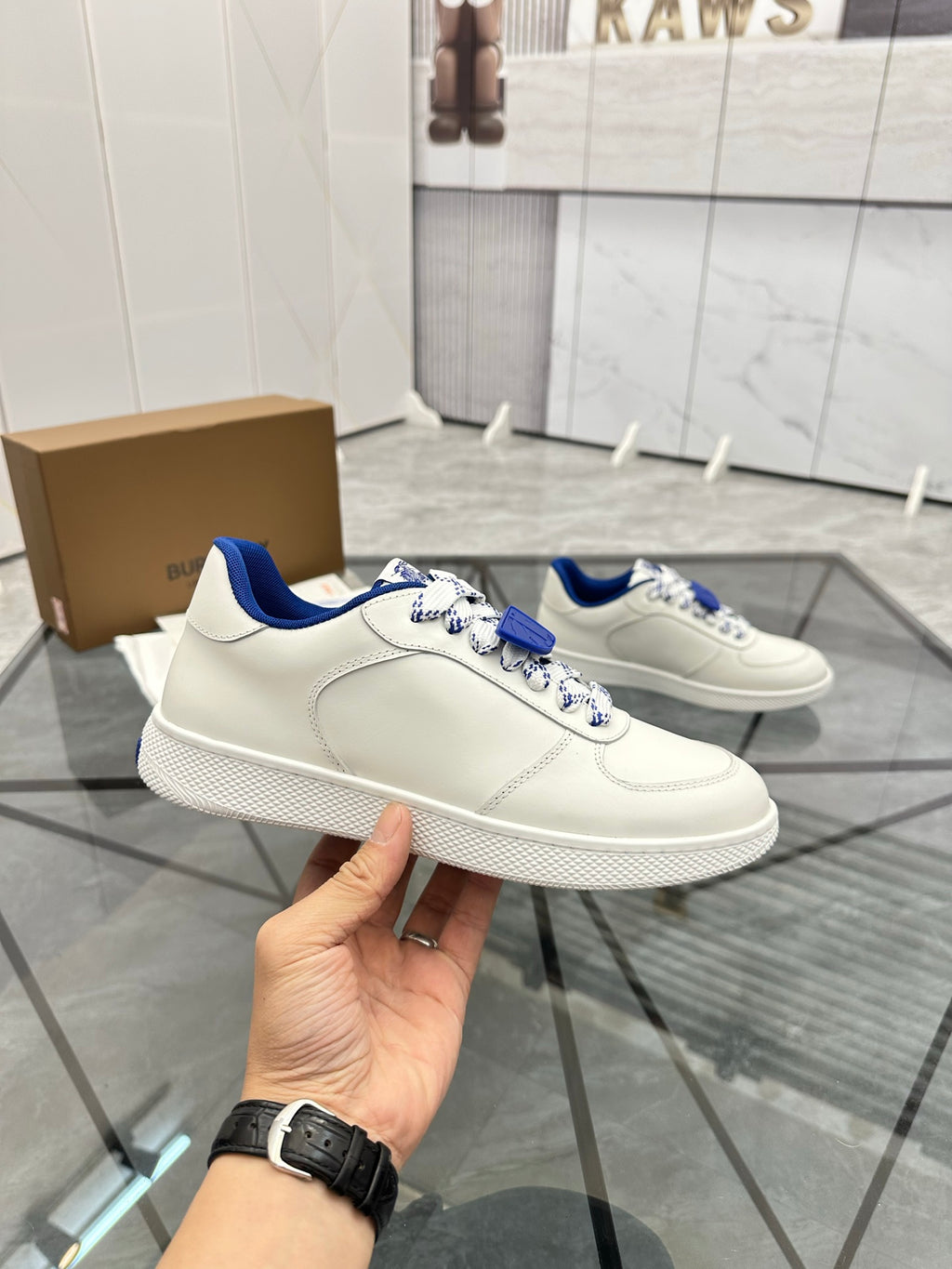 Hand-held white low-top sneaker with blue collar lining and lace strap detail