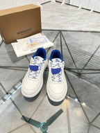 White low-top sneakers with blue lace accents and patterned toe box
