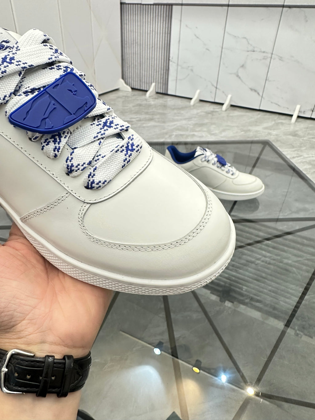 White sneaker with blue patterned lace strap and stitched panel detailing