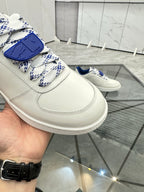 White sneaker with blue patterned lace strap and stitched panel detailing