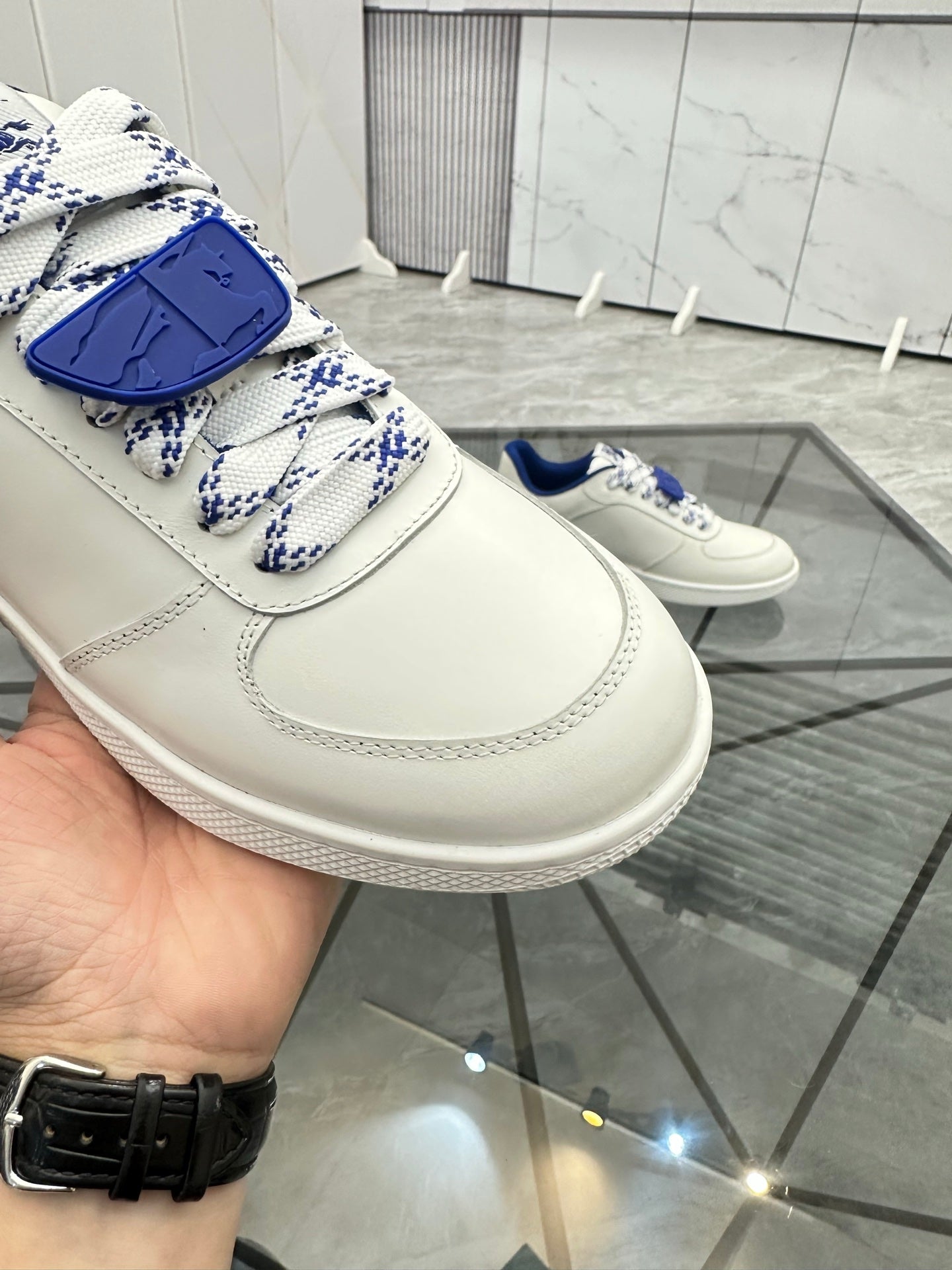 White sneaker with blue patterned lace strap and stitched panel detailing