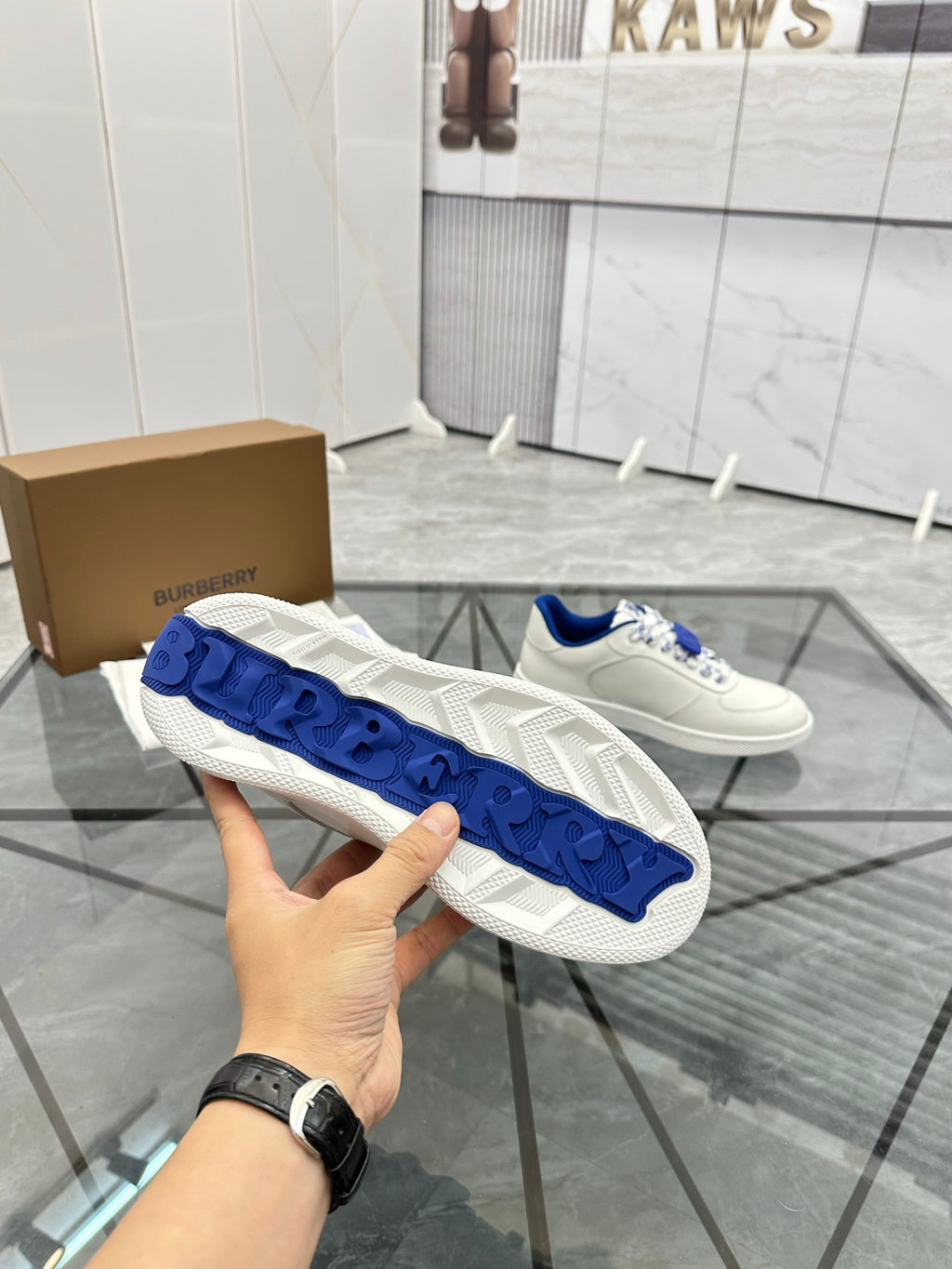 White sneaker outsole view with blue tread panels and embossed details