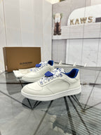 White low-top sneakers with blue heel, patterned lace panels, and textured sole