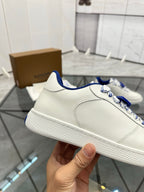 White low-top sneaker side view with blue collar and textured rubber sole