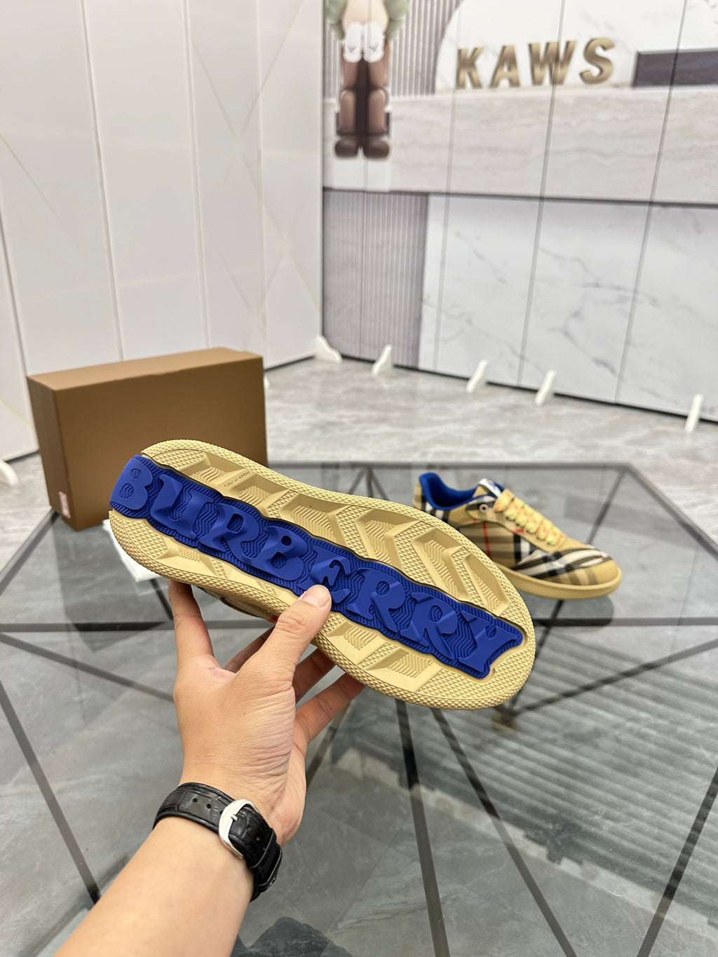 Close-up outsole of check low-top sneakers: tan rubber tread with blue side