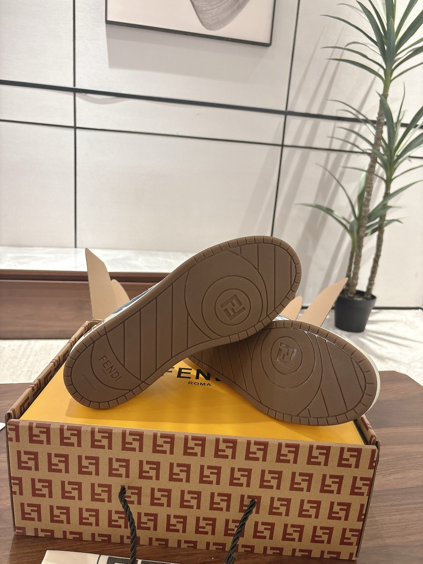 Fendi unisex sneakers outsole view, dark rubber soles with circular tread patterns.