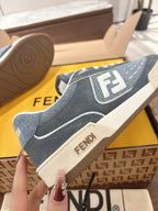 Fendi unisex sneakers side close-up, dark blue with white F logo patch and off-white sole.