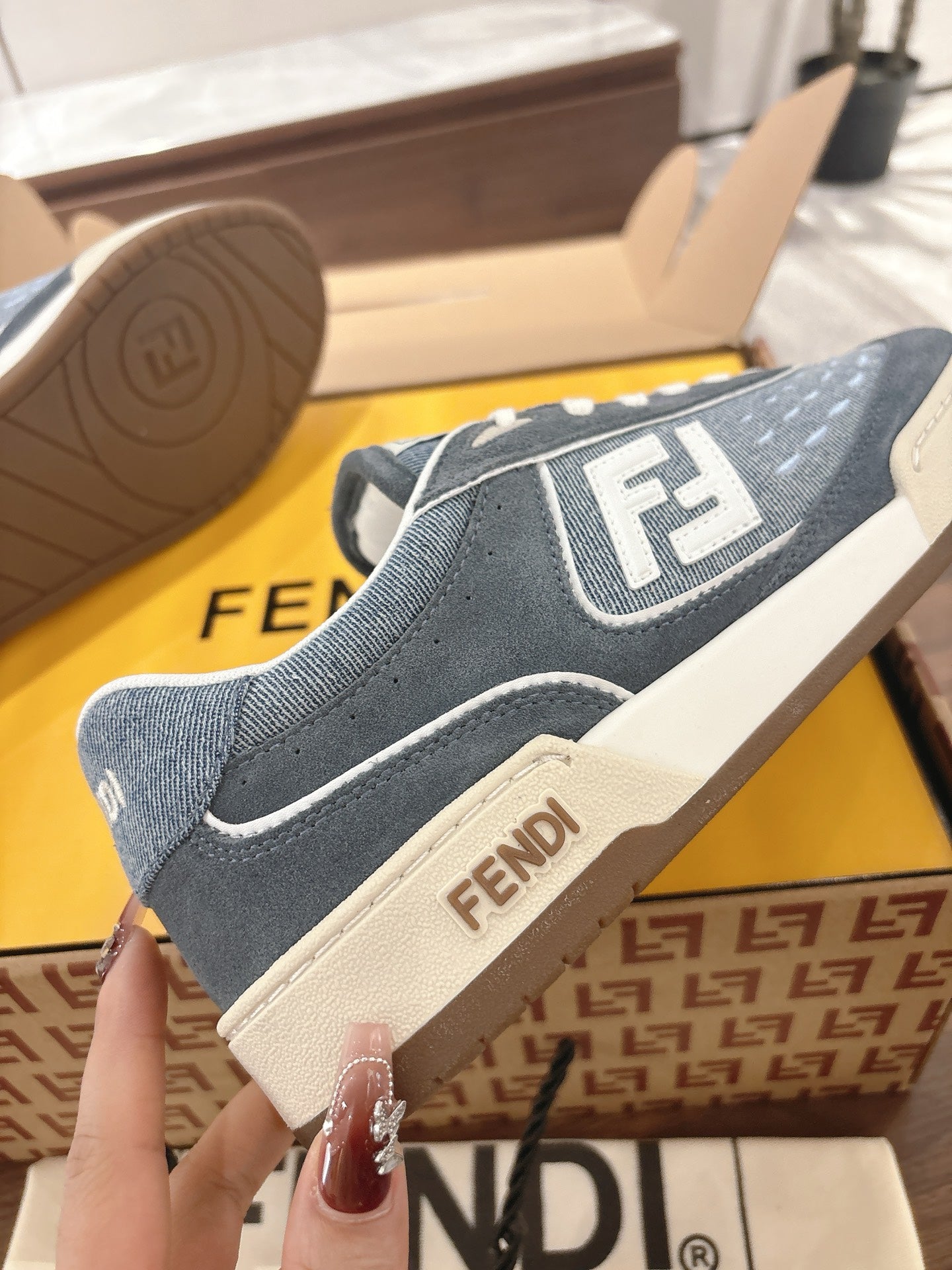 Fendi unisex sneakers side close-up, dark blue with white F logo patch and off-white sole.