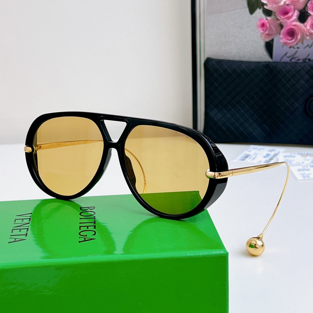 Sunglasses with black frame, gold accents, and yellow mirrored lenses.