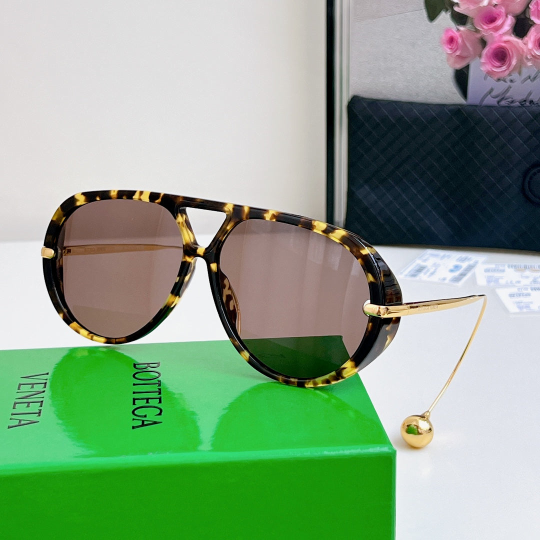 Sunglasses with tortoiseshell frame and brown tinted lenses; gold hardware.