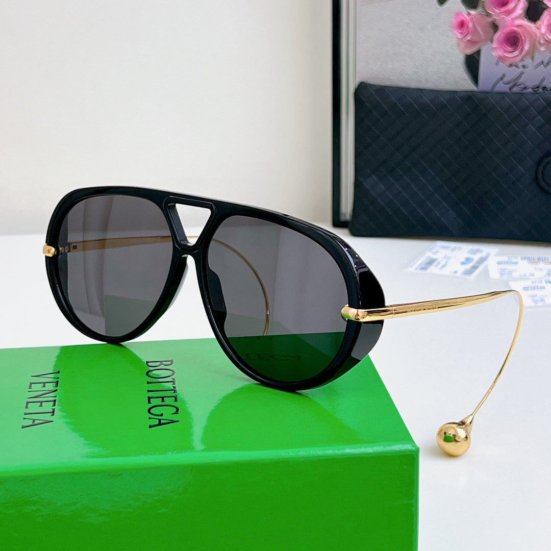 Sunglasses with black frame, gold accents, and gray mirrored lenses.