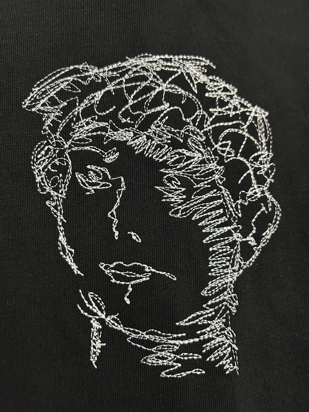Off-White T-shirt close-up of white line-art head and shoulder graphic