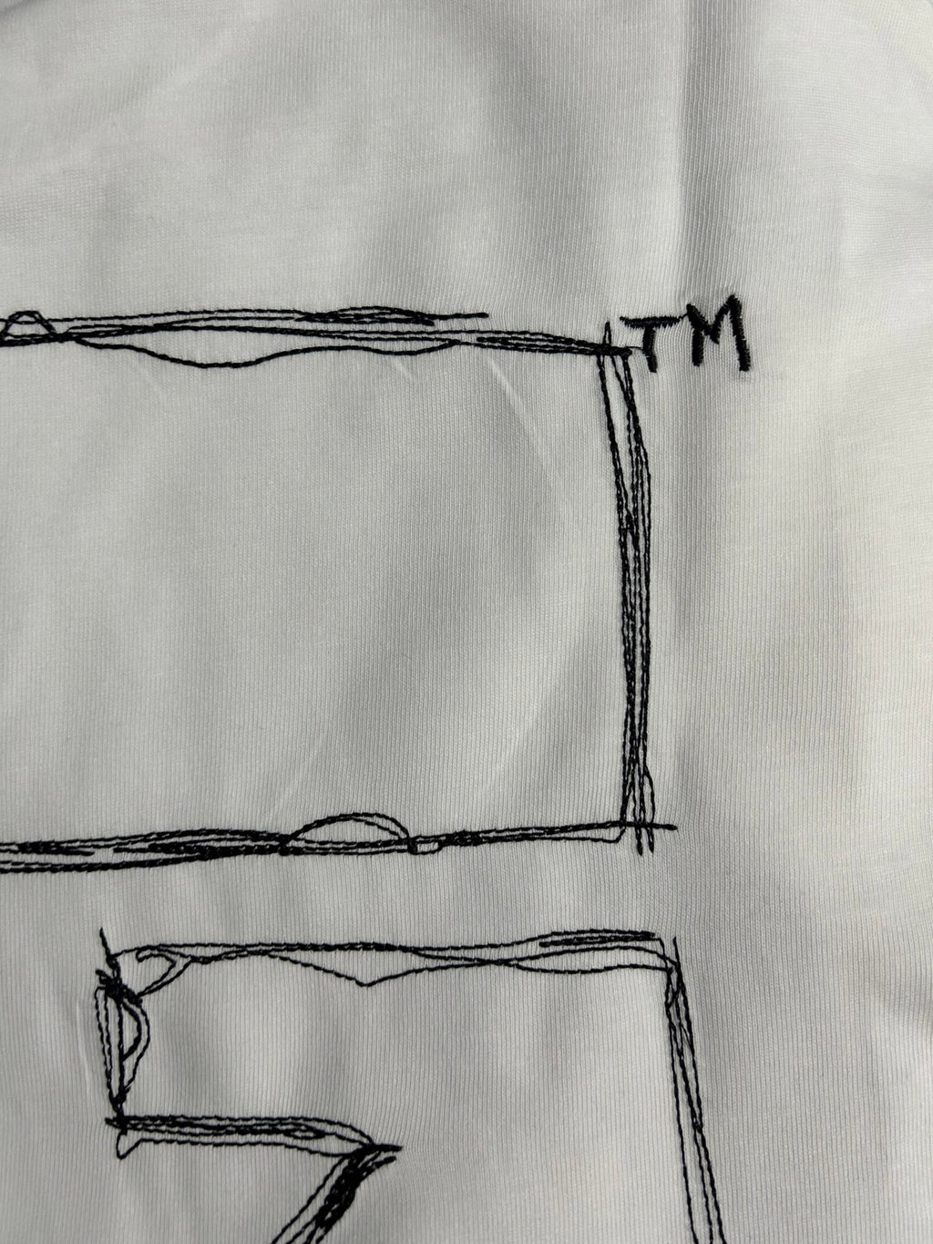 Off-White off-white T-shirt close-up of black X graphic corner and TM
