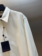 Cream textured long-sleeve shirt with buttoned chest, spread collar, and side tag