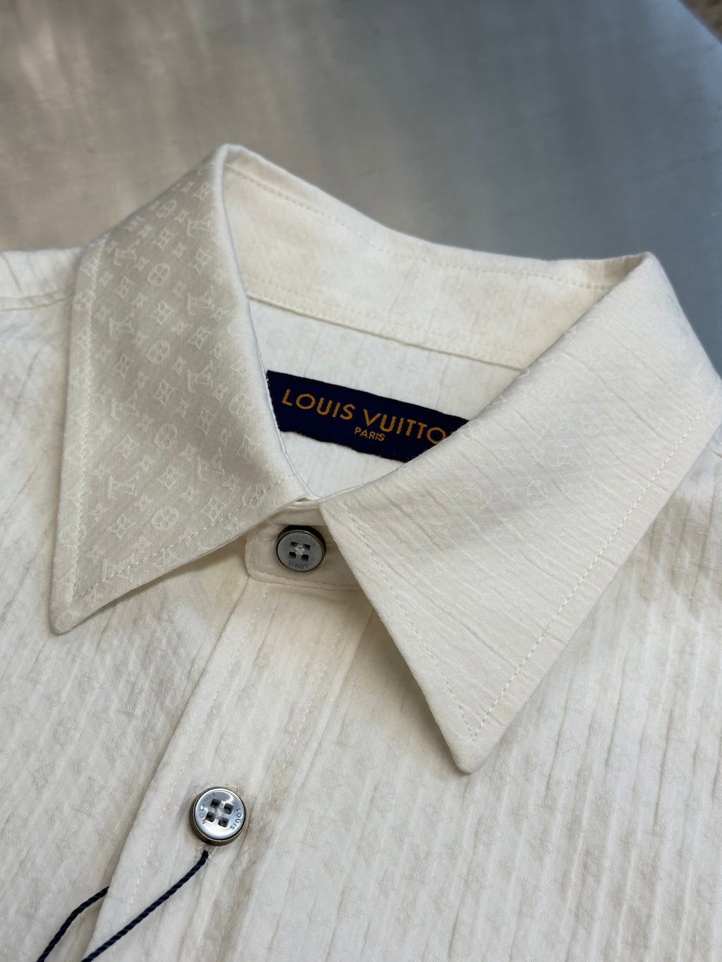 Cream long-sleeve shirt detail of spread collar and button at neckline with inner tag