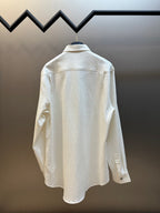 Back view of a cream long-sleeve button-up shirt with textured fabric and yoke seam