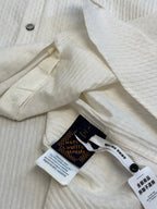Cream long-sleeve shirt with collar, buttons, and inner label tags on placket