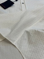 Cream textured shirt fabric close-up with top tag and collar button area