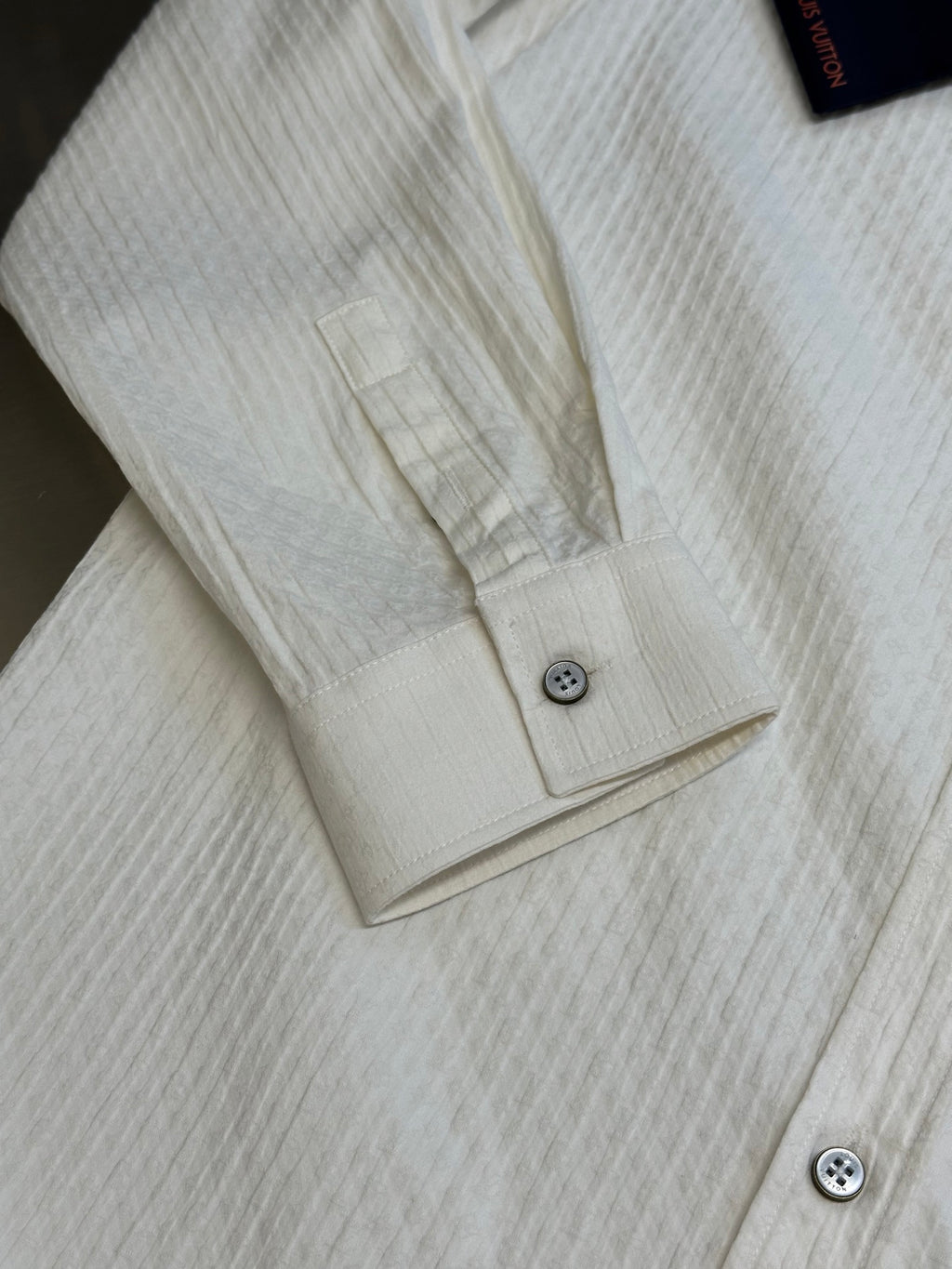 Cream long-sleeve shirt with cuff buttons and partial front placket detail