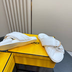 White Fendi slide sandals on a yellow box, with gold chain strap detail