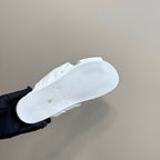 White Fendi slide sandal outsole view, held in a gloved hand
