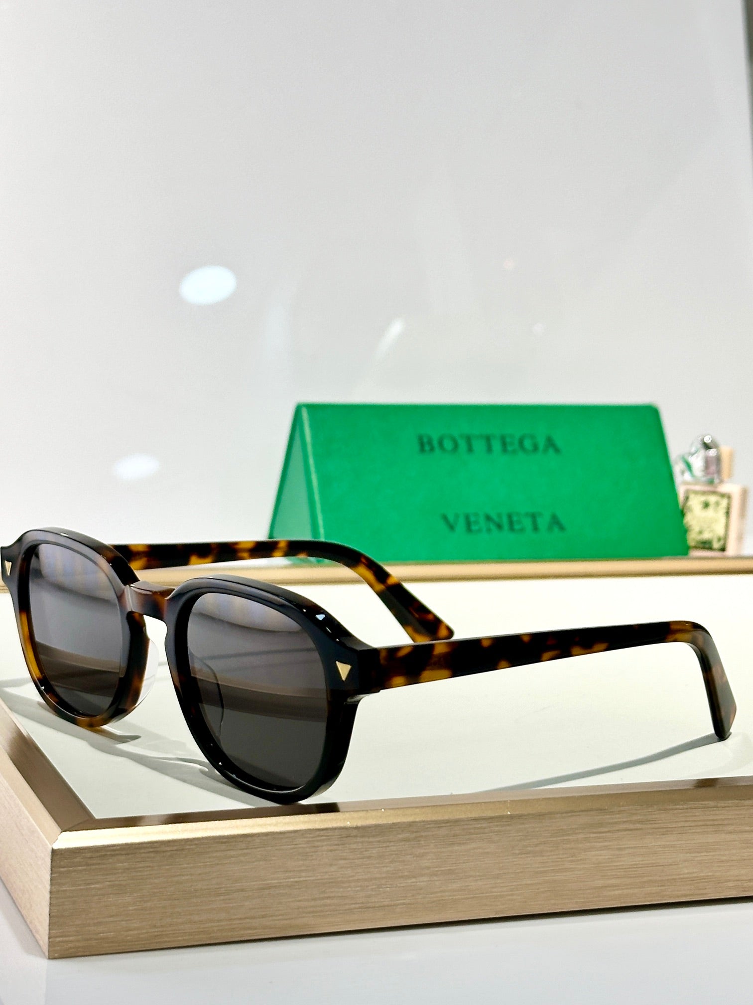 Bottega Veneta glasses with tortoiseshell accents and dark tinted lenses