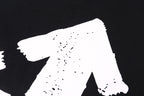 Black T-shirt close-up of large white graphic print with small speckles
