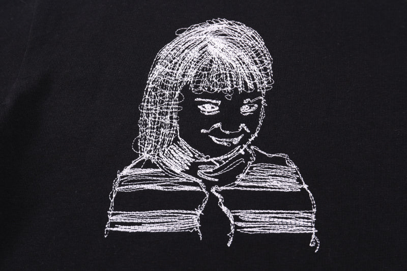 Black T-shirt close-up of line-art portrait graphic with braids