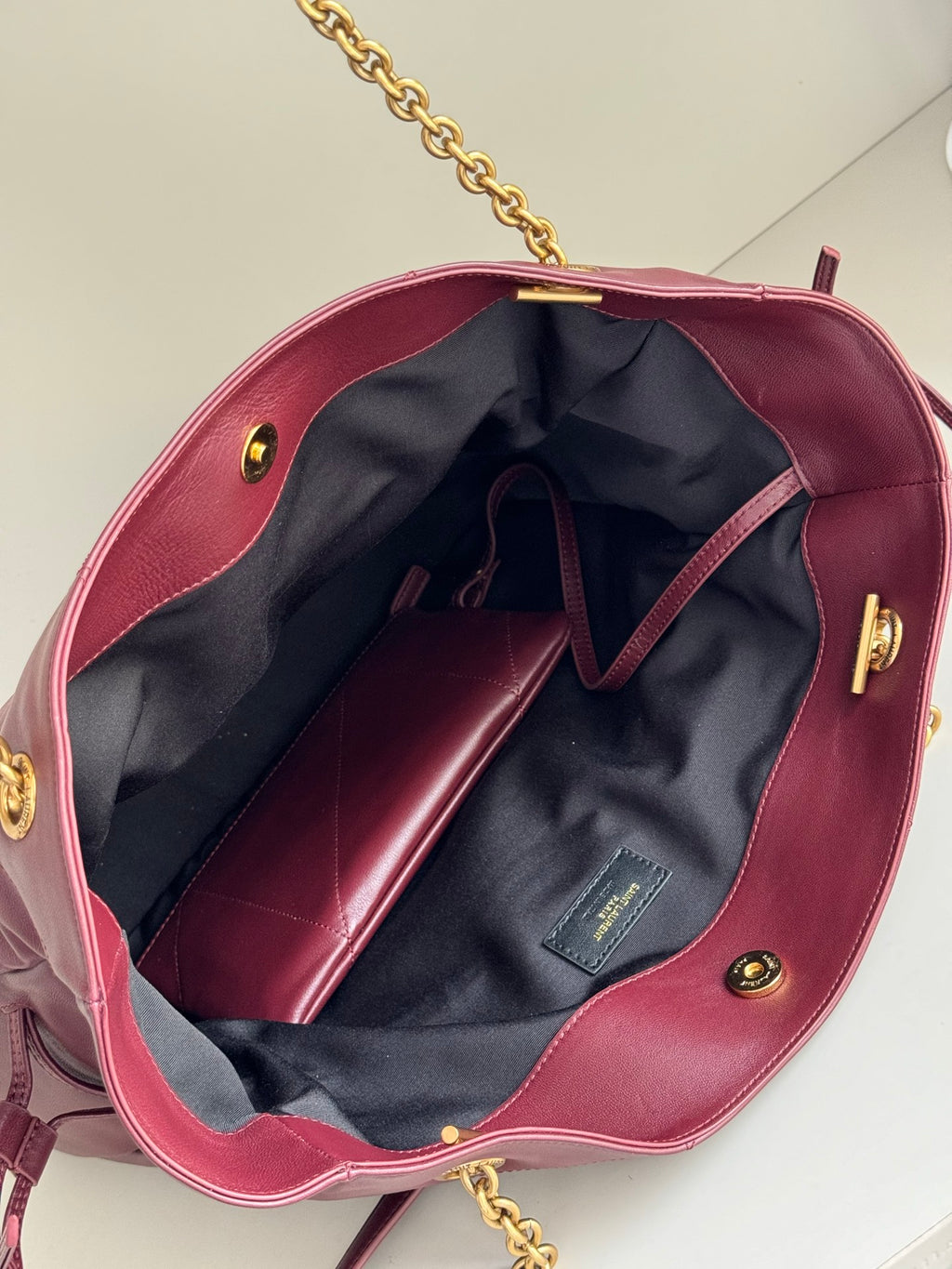 YSL burgundy tote bag interior with navy lining, open top, and gold hardware accents