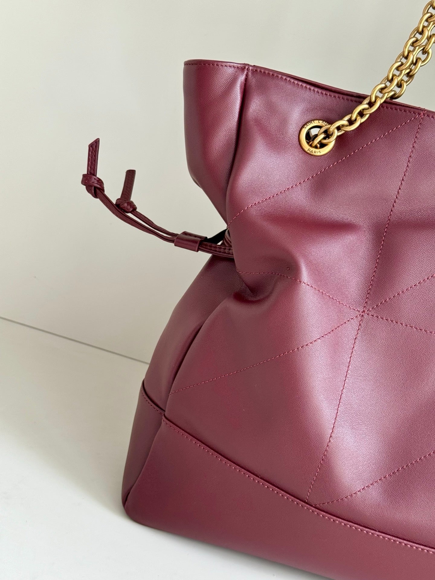 YSL burgundy leather tote with quilted panels and bow-like strap ties on side
