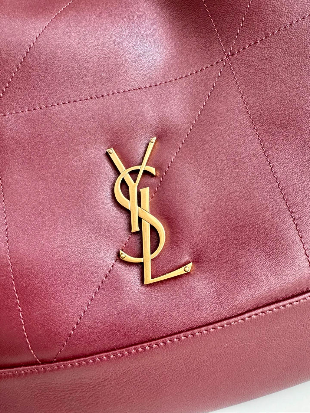YSL logo detail on burgundy leather tote, with quilted diamond stitching