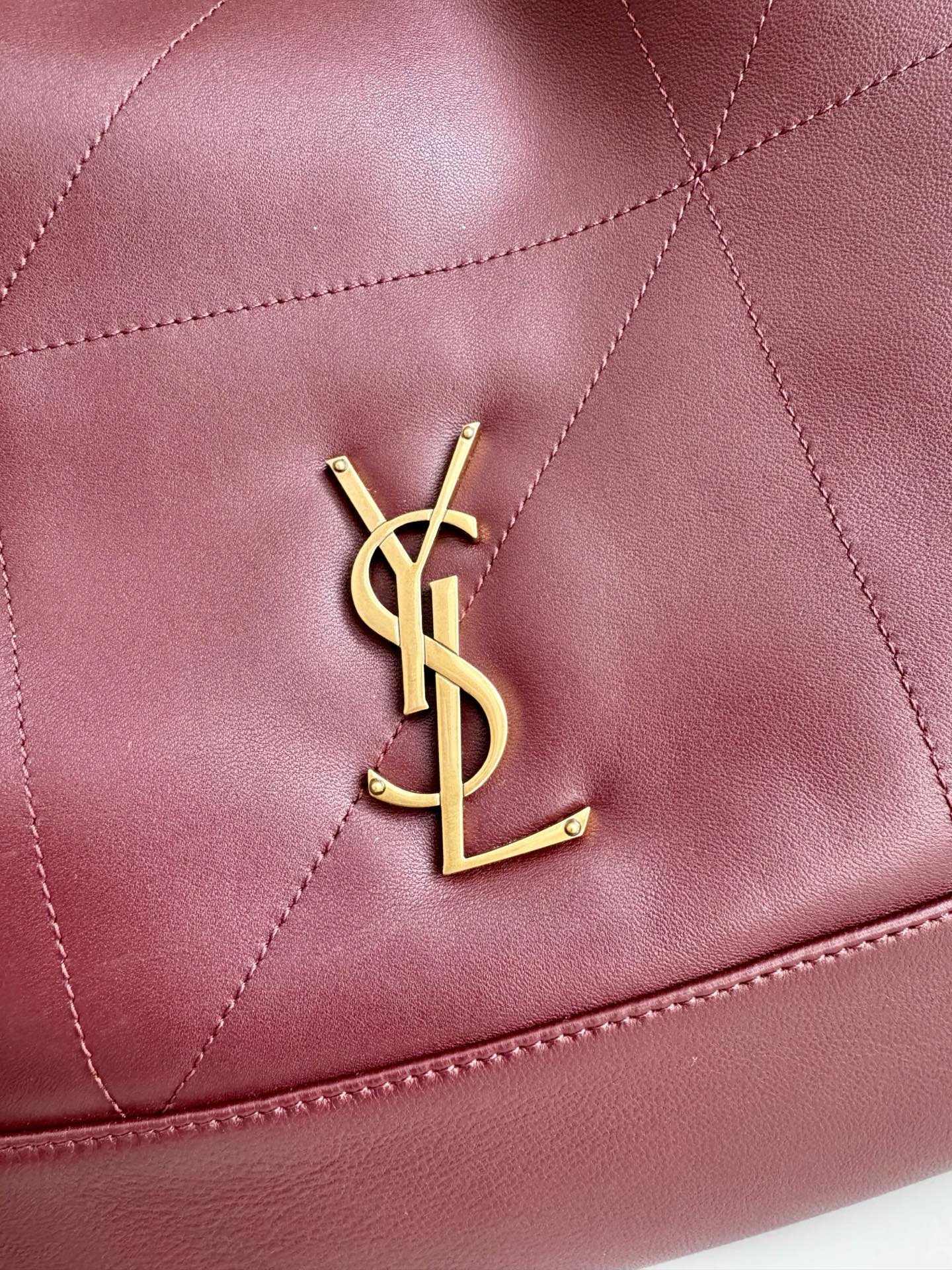 YSL logo detail on burgundy leather tote, with quilted diamond stitching