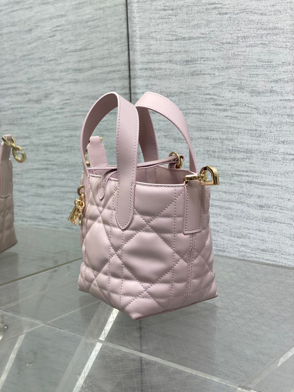 Pink Dior quilted handbag with side view, dual handles, and gold top clasp