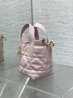 Pink Dior quilted handbag with side view, dual handles, and gold top clasp